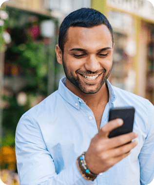 A smiling man in blue shirt looking at his phone