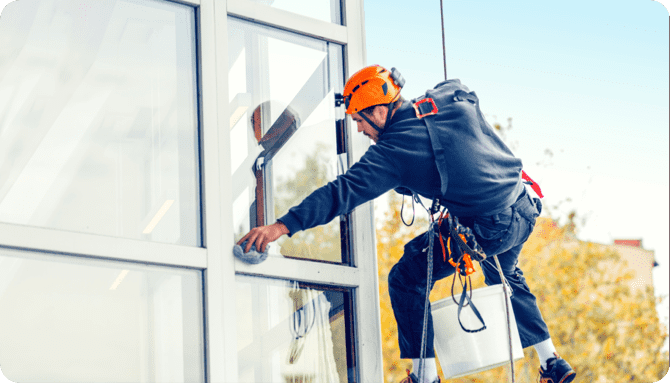a man busy cleaning a glass building from the outside