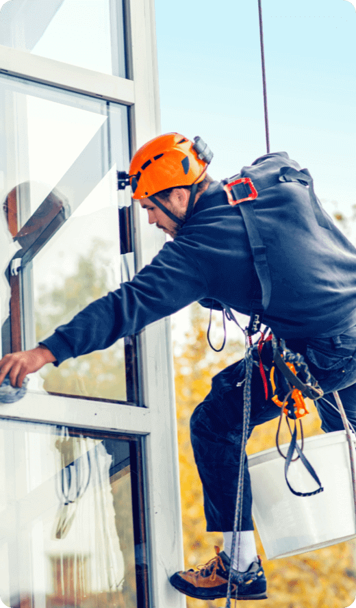 a man busy cleaning a glass building from the outside