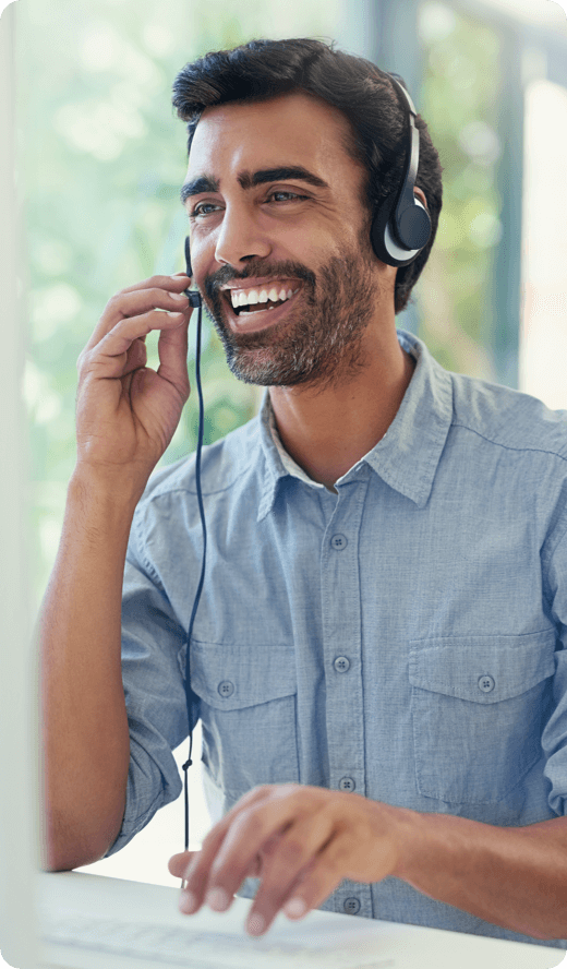 A smiling woman looking at her laptop wearing headphones