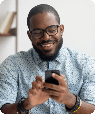 A smiling man in blue shirt looking at his phone